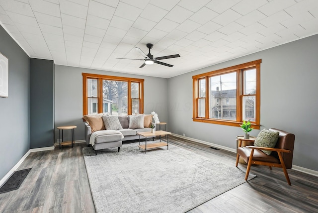 living room with visible vents, wood finished floors, a ceiling fan, and plenty of natural light