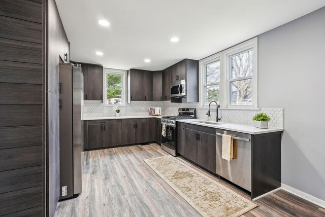 kitchen featuring decorative backsplash, light countertops, dark brown cabinets, appliances with stainless steel finishes, and a sink