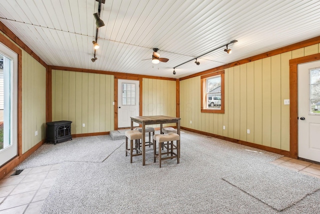 dining space featuring a wood stove, baseboards, tile patterned floors, ceiling fan, and track lighting