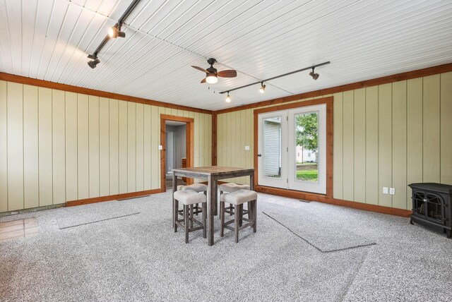 dining area with carpet flooring, a ceiling fan, track lighting, and a wood stove