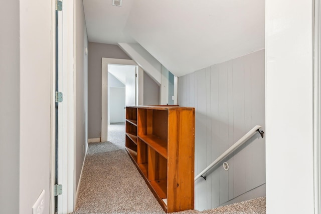 hallway with an upstairs landing, carpet, and vaulted ceiling