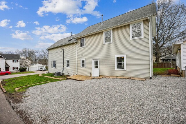 back of house with an outdoor structure, central AC unit, and a shingled roof