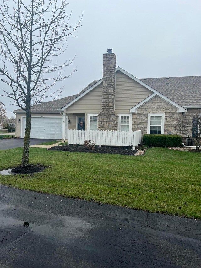 view of front of house with fence, driveway, a front yard, a garage, and a chimney