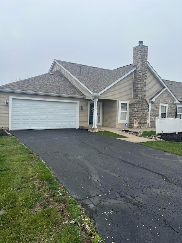 view of front of house with a chimney, a garage, aphalt driveway, and a shingled roof