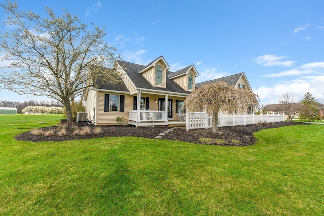 view of front of property with central air condition unit, covered porch, roof with shingles, a front yard, and fence