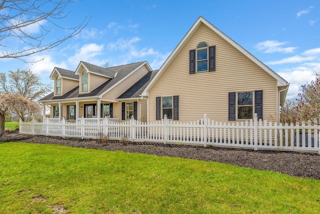 rear view of property featuring a yard, roof with shingles, and a fenced front yard
