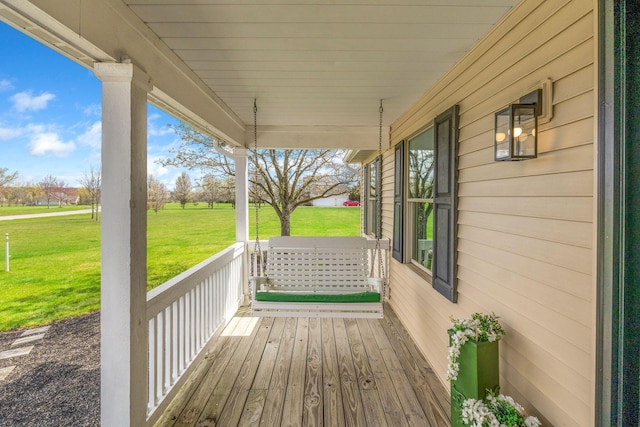 wooden terrace featuring covered porch and a lawn