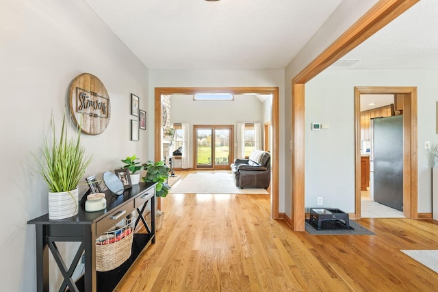 hallway featuring light wood finished floors and baseboards