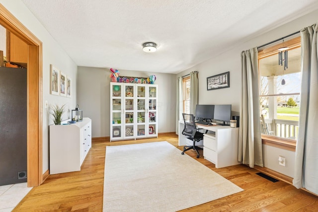 office space with baseboards, visible vents, and a wealth of natural light