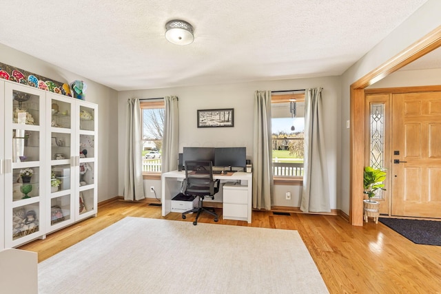 office with a textured ceiling, wood finished floors, baseboards, and visible vents