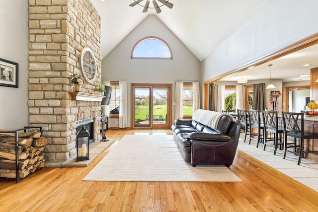 living room with a wealth of natural light, high vaulted ceiling, wood finished floors, and a fireplace