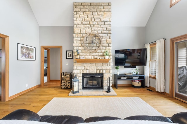 living room featuring baseboards, high vaulted ceiling, wood finished floors, and a fireplace
