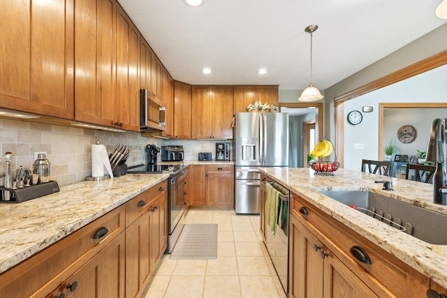 kitchen with brown cabinets, tasteful backsplash, light stone counters, and stainless steel appliances
