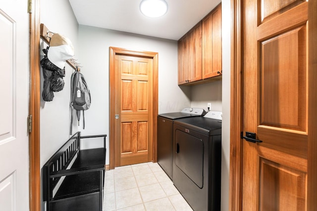 laundry area featuring separate washer and dryer, light tile patterned flooring, and cabinet space