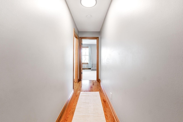 hall with light wood-style floors and baseboards