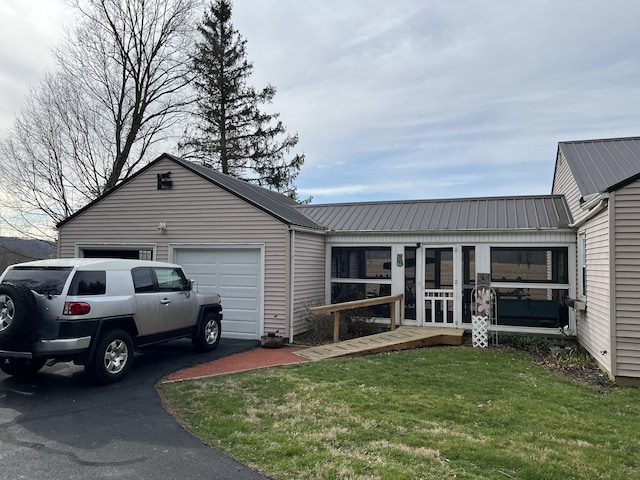 view of front of property featuring an attached garage, a front lawn, metal roof, and aphalt driveway