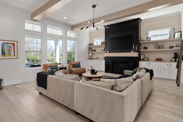 living area featuring light wood-style flooring, beamed ceiling, a high end fireplace, and baseboards
