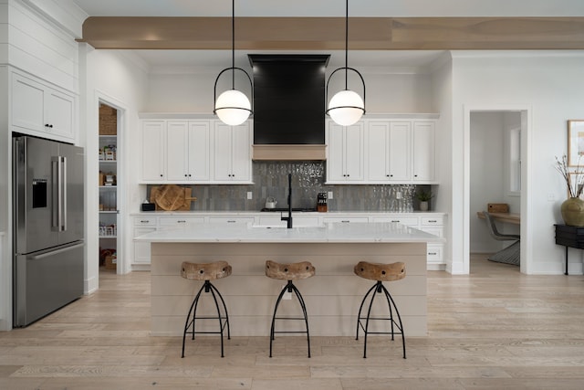 kitchen with decorative backsplash, light wood-style floors, high end refrigerator, and a breakfast bar