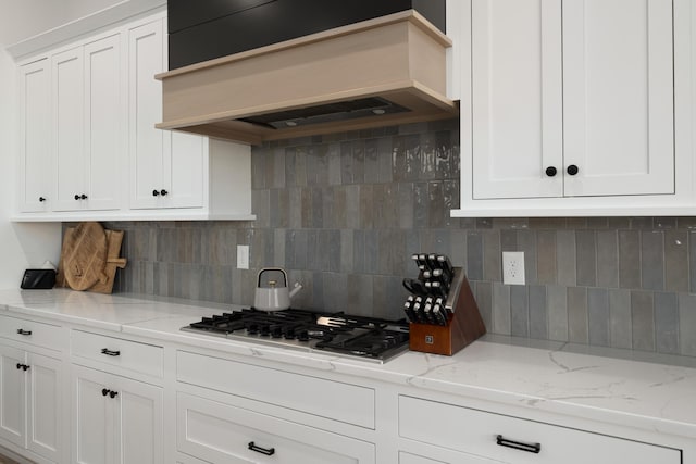 kitchen with custom range hood, white cabinetry, and stainless steel gas stovetop