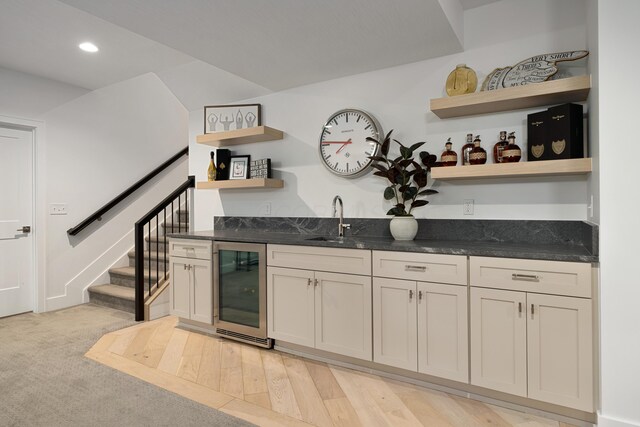 bar featuring a sink, wet bar, recessed lighting, stairs, and beverage cooler