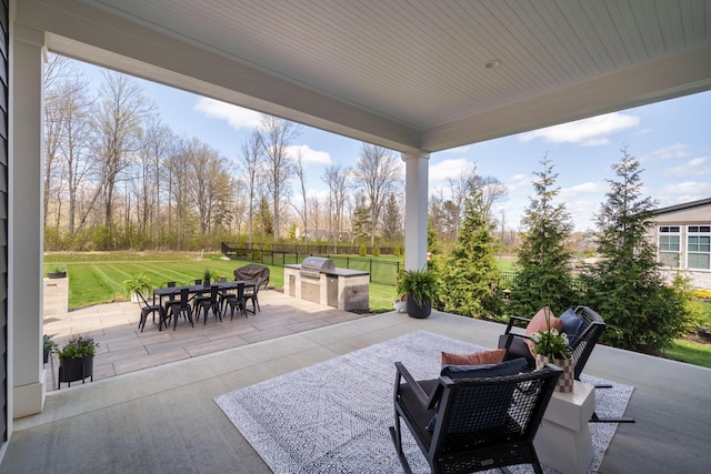 view of patio with outdoor dining space, area for grilling, fence, and exterior kitchen
