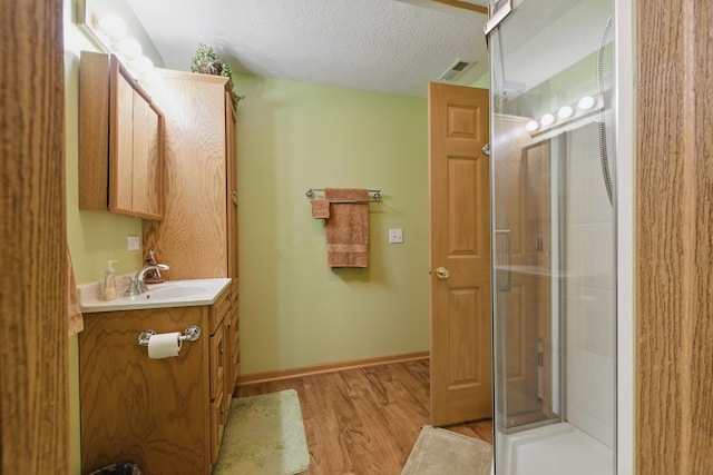 1397 Underwood Farms Blvd, Columbus, OH 43230 - bathroom featuring a textured ceiling, visible vents, a shower with door, wood finished floors, and vanity