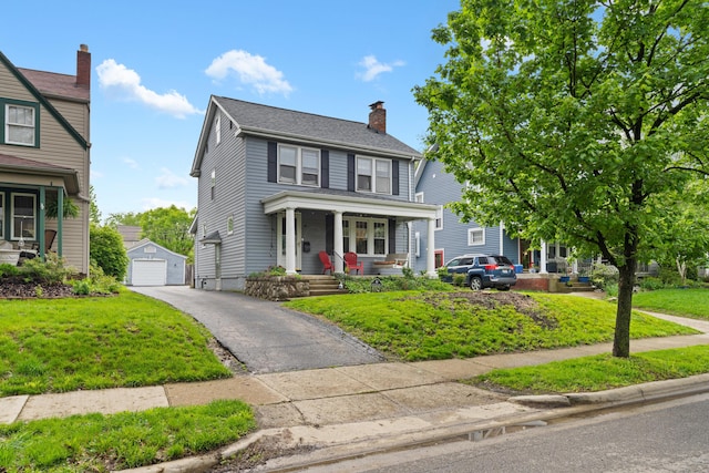 american foursquare style home featuring an outdoor structure, covered porch, a front lawn, and a chimney