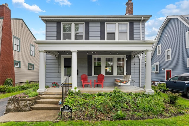 american foursquare style home with a porch and a chimney
