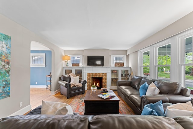 living room with arched walkways, wood finished floors, plenty of natural light, and baseboards