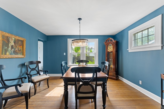 dining room with healthy amount of natural light, baseboards, a chandelier, and wood finished floors