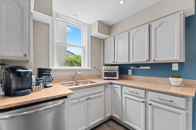 kitchen with stainless steel dishwasher, a sink, white cabinetry, and recessed lighting