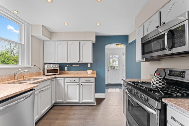 kitchen featuring stainless steel appliances, a sink, healthy amount of natural light, arched walkways, and recessed lighting