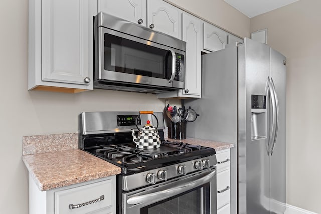kitchen featuring stainless steel appliances, light countertops, and white cabinets