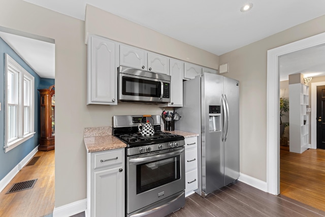 kitchen with appliances with stainless steel finishes, dark wood-style floors, baseboards, and white cabinetry