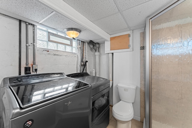 laundry area with washing machine and clothes dryer and concrete block wall