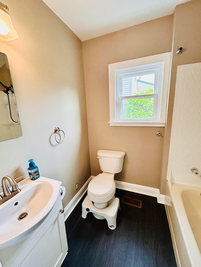 bathroom with toilet, baseboards, vanity, and wood finished floors
