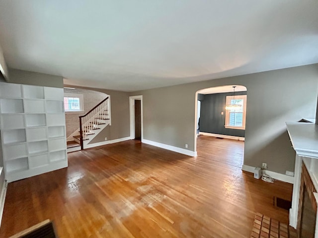 742 S Cassingham Rd, Bexley, OH 43209 - unfurnished living room featuring healthy amount of natural light, wood finished floors, arched walkways, and stairway