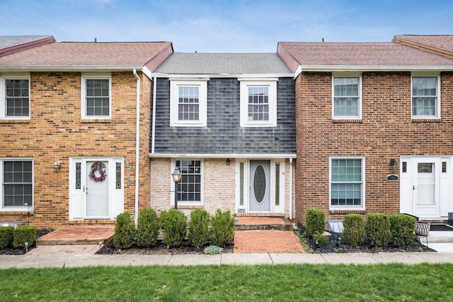 view of front of house with a shingled roof and brick siding