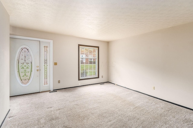 carpeted foyer featuring a textured ceiling and visible vents