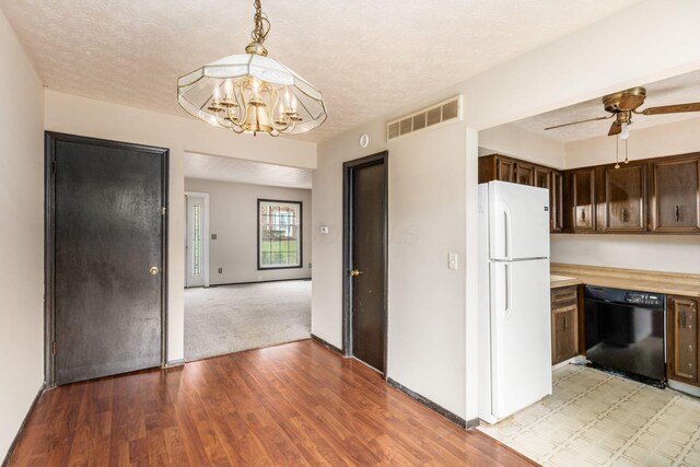 kitchen featuring light countertops, visible vents, freestanding refrigerator, black dishwasher, and dark brown cabinetry