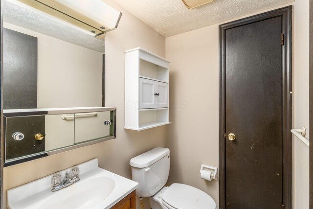 half bath featuring toilet, vanity, and a textured ceiling