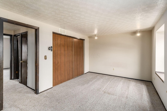 spare room with carpet floors, a textured ceiling, and visible vents
