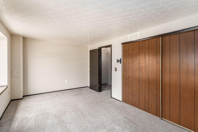 empty room featuring light carpet, a textured ceiling, and visible vents