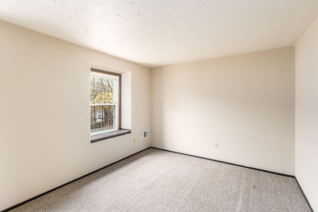 unfurnished room with light colored carpet, visible vents, baseboards, and a textured ceiling