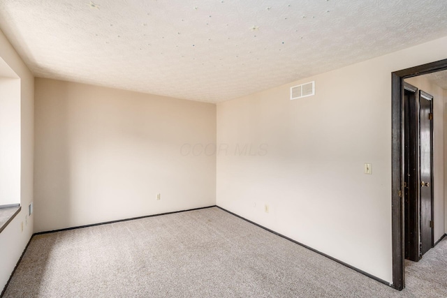 spare room with baseboards, visible vents, carpet flooring, and a textured ceiling