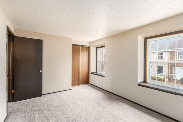 unfurnished bedroom featuring light carpet, a closet, and a textured ceiling
