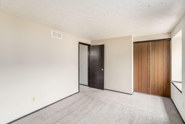 unfurnished bedroom with visible vents, a closet, carpet flooring, and a textured ceiling
