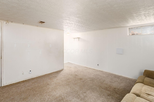 below grade area featuring carpet flooring, a textured ceiling, and visible vents