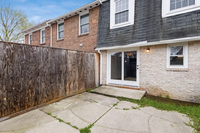 back of property with fence, mansard roof, and roof with shingles
