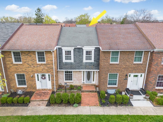 view of front of house featuring brick siding and roof with shingles